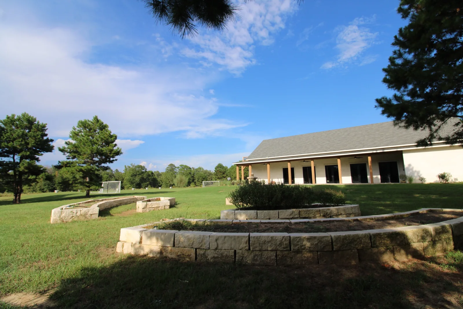 Curved stone garden walls and plantings across the lawn from the covered porch